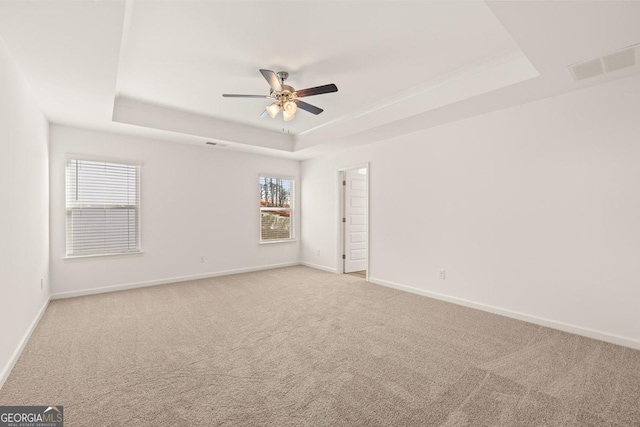 unfurnished room featuring light carpet, a raised ceiling, and ceiling fan