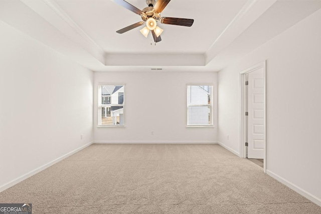 unfurnished room featuring ornamental molding, light colored carpet, ceiling fan, and a tray ceiling