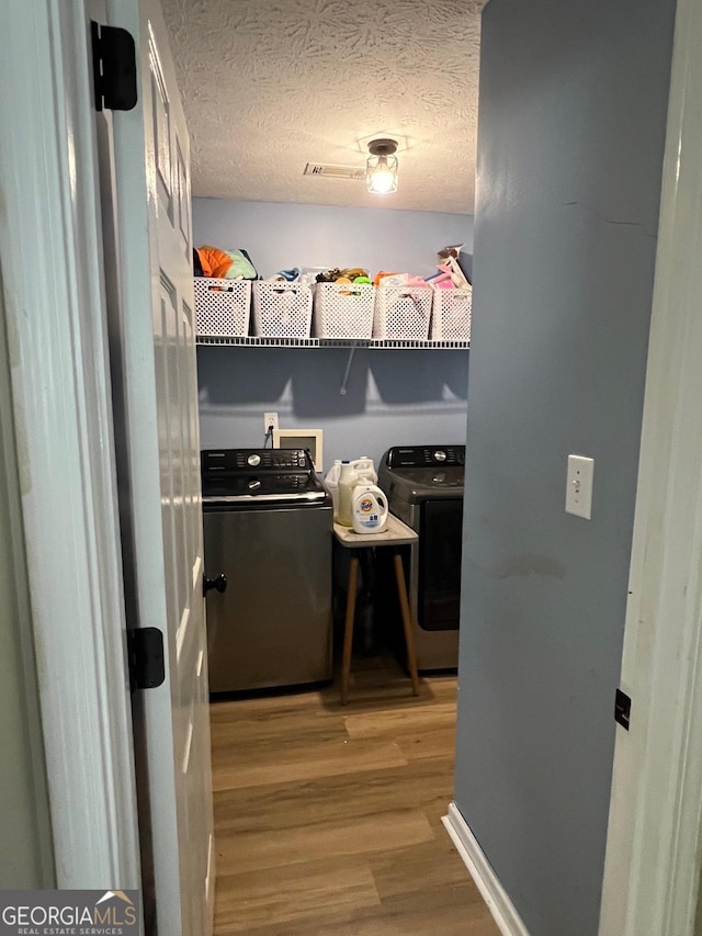 laundry room featuring hardwood / wood-style flooring, a textured ceiling, and washer and clothes dryer