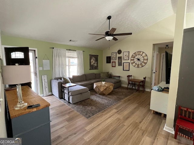 living room featuring lofted ceiling, wood-type flooring, a textured ceiling, and ceiling fan