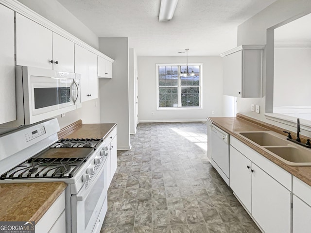 kitchen with white appliances, hanging light fixtures, a textured ceiling, white cabinetry, and sink