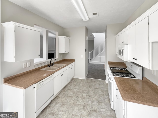 kitchen featuring sink, white appliances, and white cabinetry