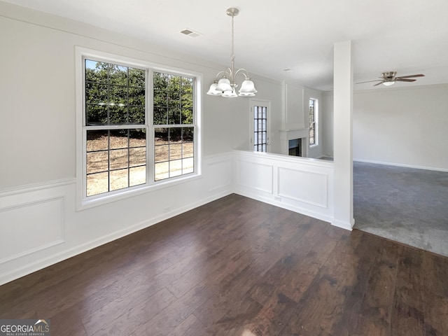 unfurnished dining area with ceiling fan with notable chandelier and dark wood-type flooring