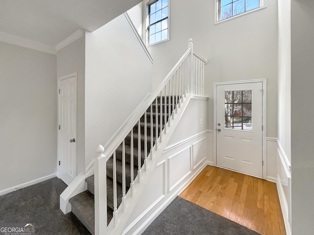 stairs with hardwood / wood-style floors, plenty of natural light, and crown molding