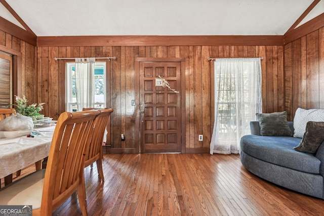 interior space with wood walls, vaulted ceiling, and hardwood / wood-style floors