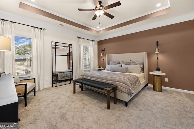 bedroom with ceiling fan, light colored carpet, ornamental molding, and a tray ceiling