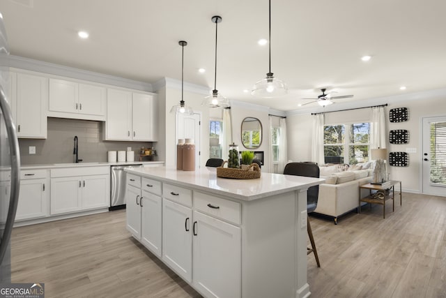 kitchen with hanging light fixtures, a center island, sink, white cabinetry, and stainless steel dishwasher