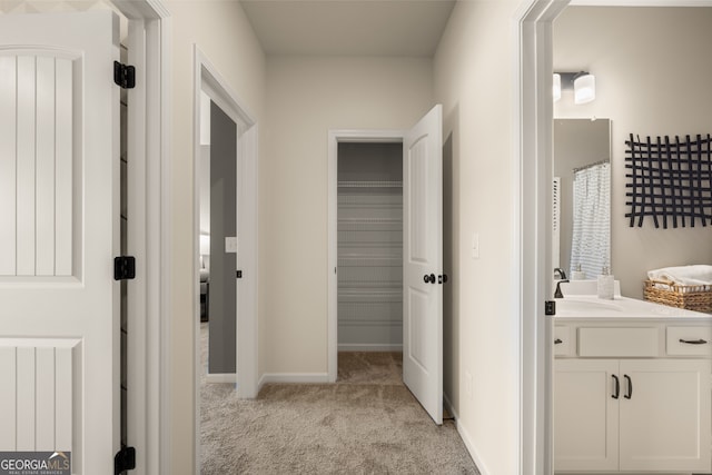 corridor featuring radiator, light carpet, and sink