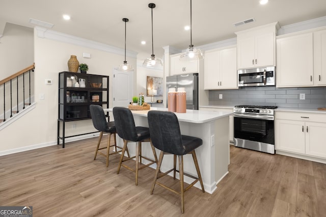 kitchen featuring appliances with stainless steel finishes, pendant lighting, white cabinetry, and a center island