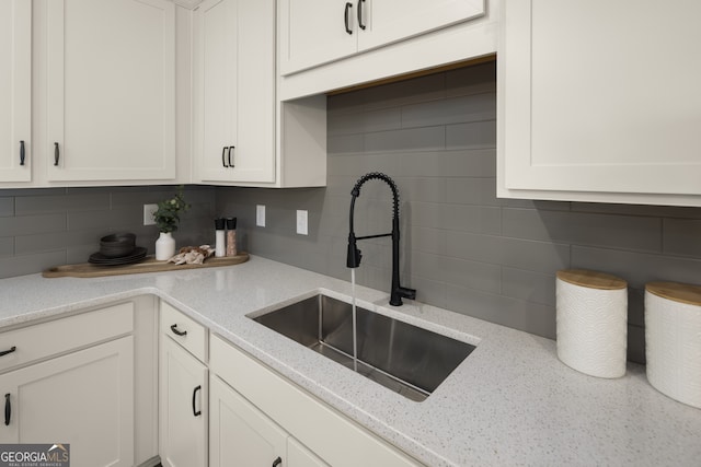 kitchen with sink, white cabinetry, light stone countertops, and tasteful backsplash