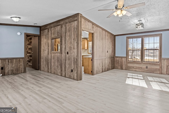 interior space featuring light wood-type flooring, a textured ceiling, ceiling fan, and crown molding