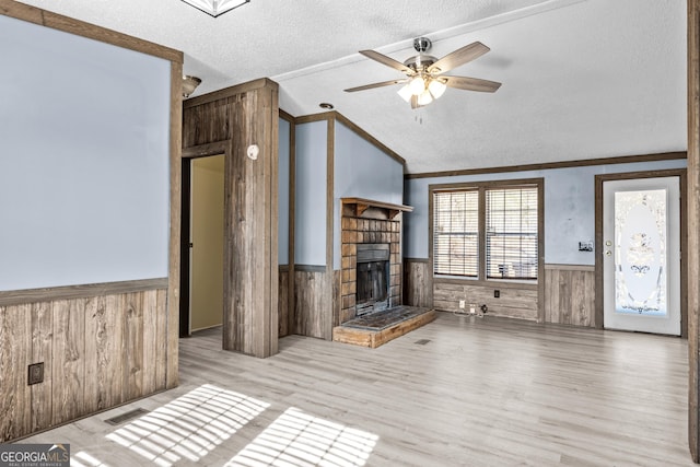 unfurnished living room with vaulted ceiling, ornamental molding, a textured ceiling, and ceiling fan