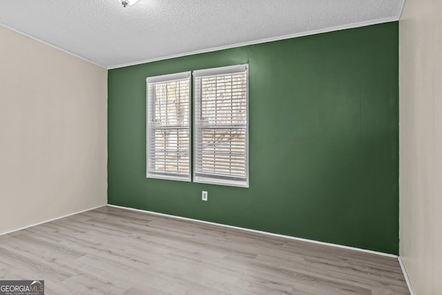 spare room featuring a textured ceiling and light hardwood / wood-style floors