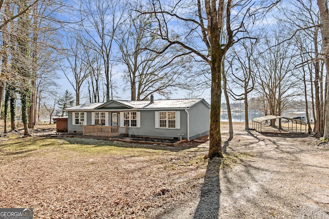 ranch-style house featuring a deck with water view and a carport