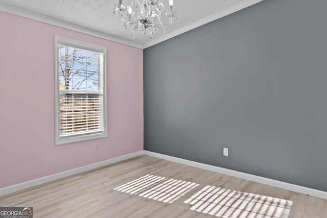 empty room with ornamental molding, a textured ceiling, light wood-type flooring, and a chandelier