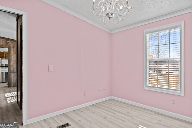 unfurnished room featuring a textured ceiling, light wood-type flooring, an inviting chandelier, and crown molding