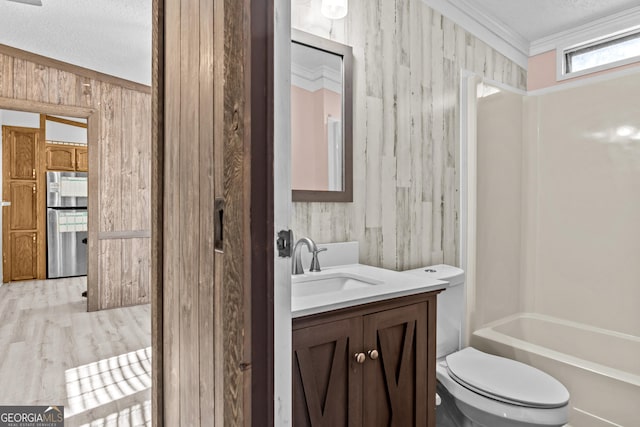 bathroom featuring a textured ceiling, toilet, wood walls, vanity, and crown molding