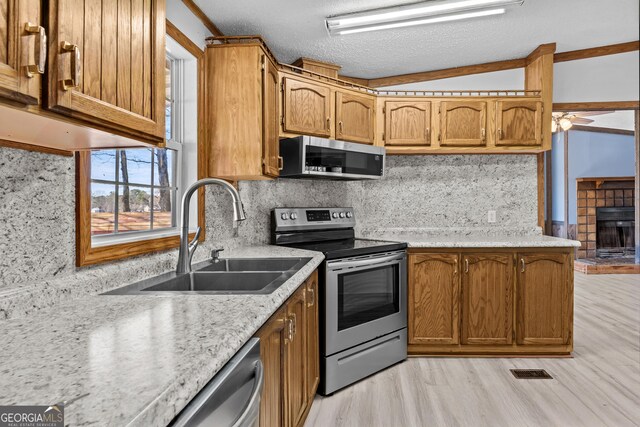 kitchen with appliances with stainless steel finishes, ceiling fan, a textured ceiling, decorative backsplash, and sink