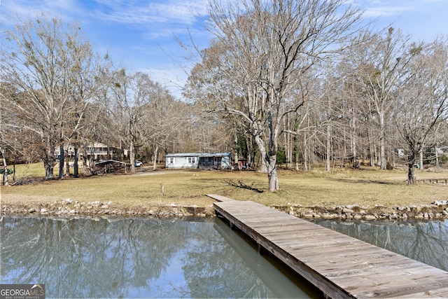 view of dock with a yard and a water view