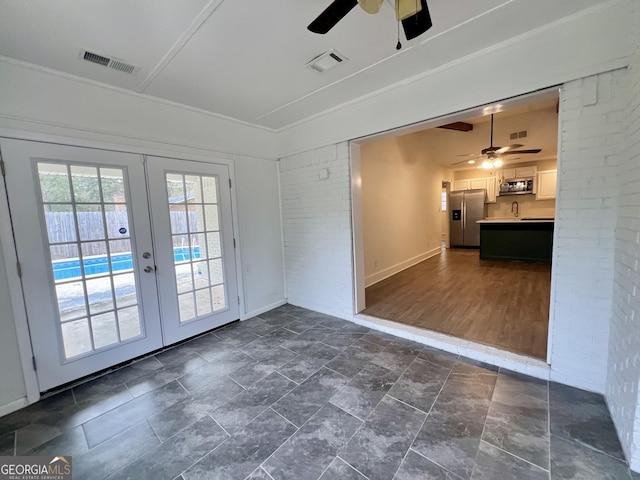 interior space with crown molding, brick wall, ceiling fan, french doors, and sink