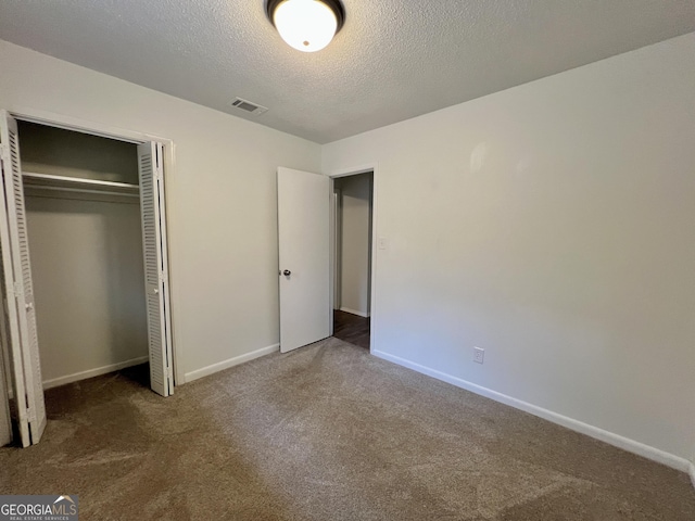 unfurnished bedroom featuring a textured ceiling, a closet, and carpet flooring