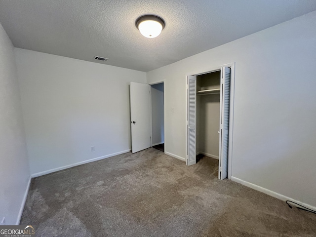 unfurnished bedroom with a textured ceiling, a closet, and carpet