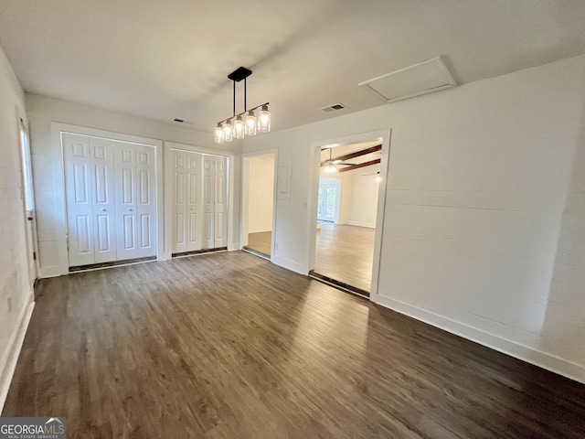 unfurnished bedroom featuring multiple closets and dark hardwood / wood-style floors