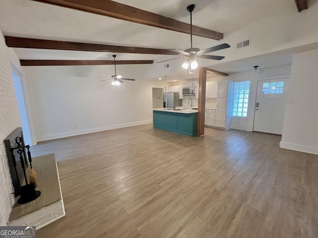 unfurnished living room featuring ceiling fan, light hardwood / wood-style flooring, and lofted ceiling with beams