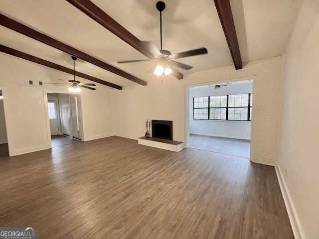 unfurnished living room with a fireplace, ceiling fan, dark hardwood / wood-style flooring, and vaulted ceiling with beams