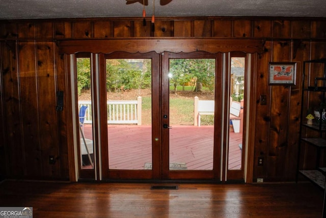 entryway with wooden walls, a textured ceiling, ceiling fan, a healthy amount of sunlight, and dark wood-type flooring