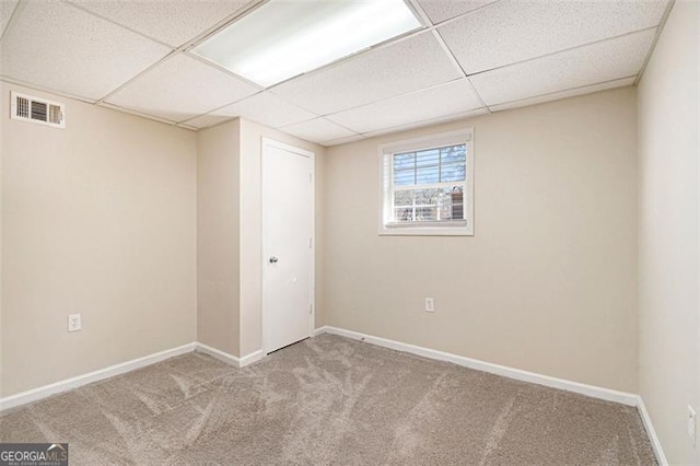 unfurnished room with light colored carpet and a drop ceiling