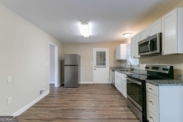 kitchen featuring dark stone countertops, stainless steel appliances, dark hardwood / wood-style flooring, sink, and white cabinetry