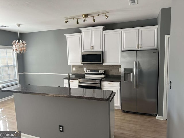 kitchen with white cabinets, stainless steel appliances, an inviting chandelier, and decorative backsplash