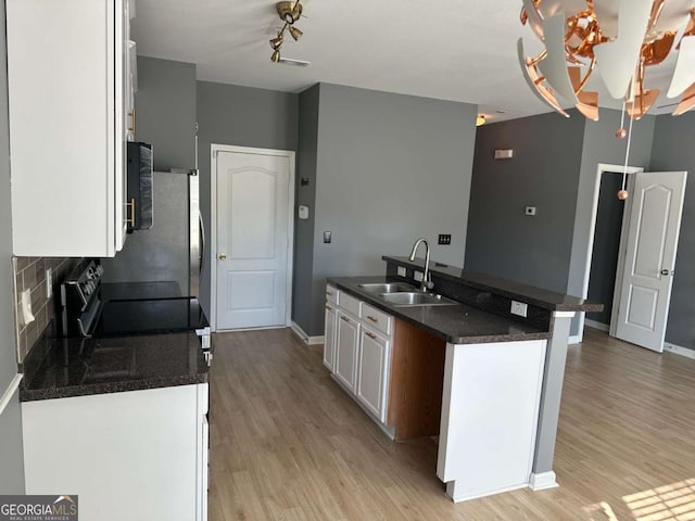 kitchen with a notable chandelier, light hardwood / wood-style flooring, white cabinetry, and sink