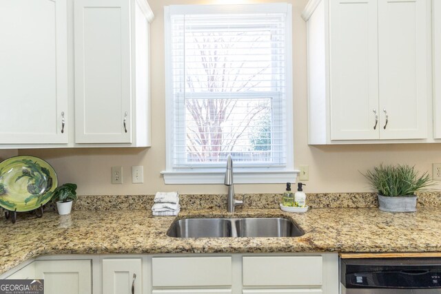 kitchen featuring dishwashing machine, white cabinets, light stone counters, and sink