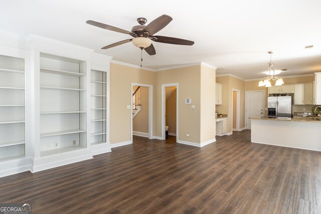 unfurnished living room with ceiling fan with notable chandelier, dark wood-type flooring, built in features, and crown molding