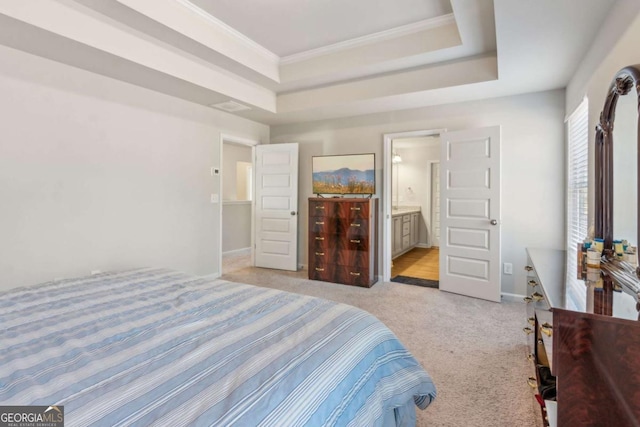 carpeted bedroom featuring ornamental molding, ensuite bath, and a raised ceiling