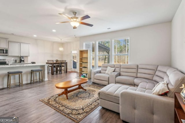 living room featuring ceiling fan and dark hardwood / wood-style floors