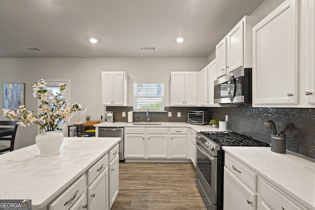 kitchen featuring sink, stainless steel appliances, white cabinetry, and backsplash