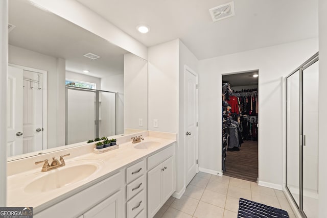 bathroom featuring a shower with shower door, vanity, and tile patterned flooring