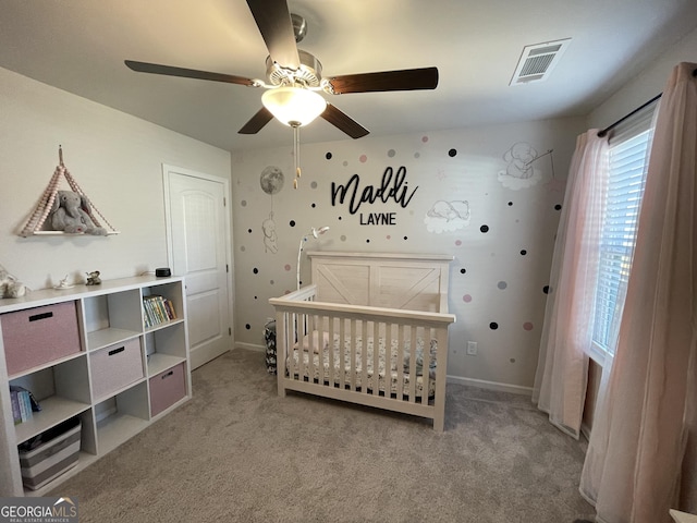 bedroom with ceiling fan, a nursery area, and light carpet