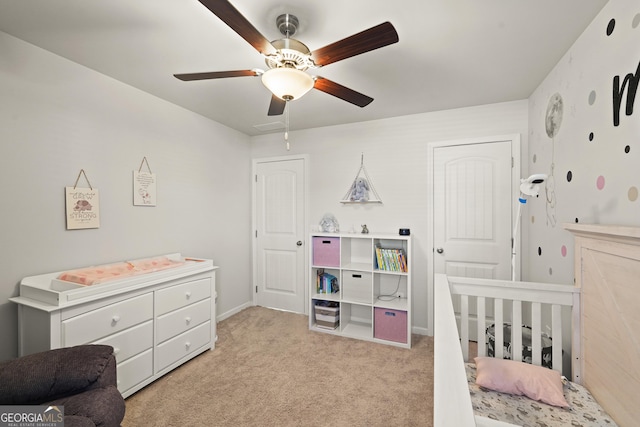 bedroom featuring light carpet, ceiling fan, and a nursery area