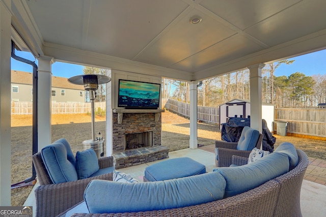 view of patio with an outdoor living space with a fireplace and a storage unit