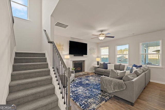 living room featuring ceiling fan, a fireplace, and wood-type flooring