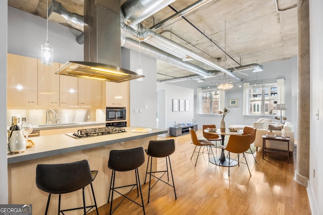 kitchen with sink, stainless steel gas cooktop, light brown cabinetry, island range hood, and built in microwave