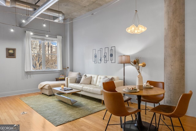 living room with a towering ceiling, hardwood / wood-style flooring, and an inviting chandelier