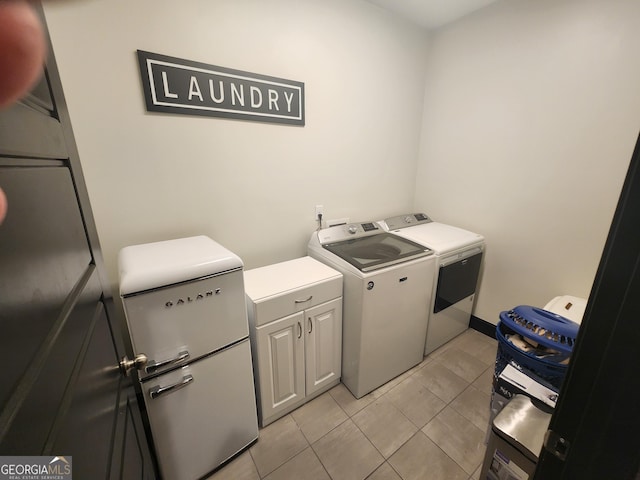 clothes washing area featuring cabinet space, washer and clothes dryer, and light tile patterned floors