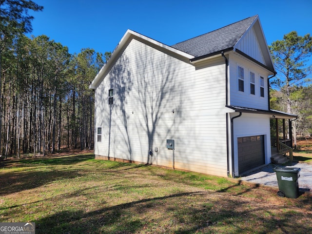 view of property exterior with roof with shingles, a lawn, and an attached garage