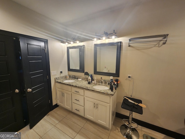 bathroom featuring double vanity, tile patterned flooring, a sink, and baseboards