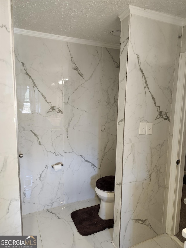 bathroom featuring ornamental molding, toilet, and a textured ceiling